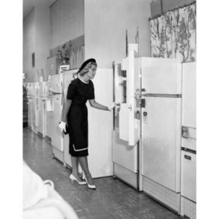 Young woman looking at refrigerators in a store Poster Print (18 x 24)